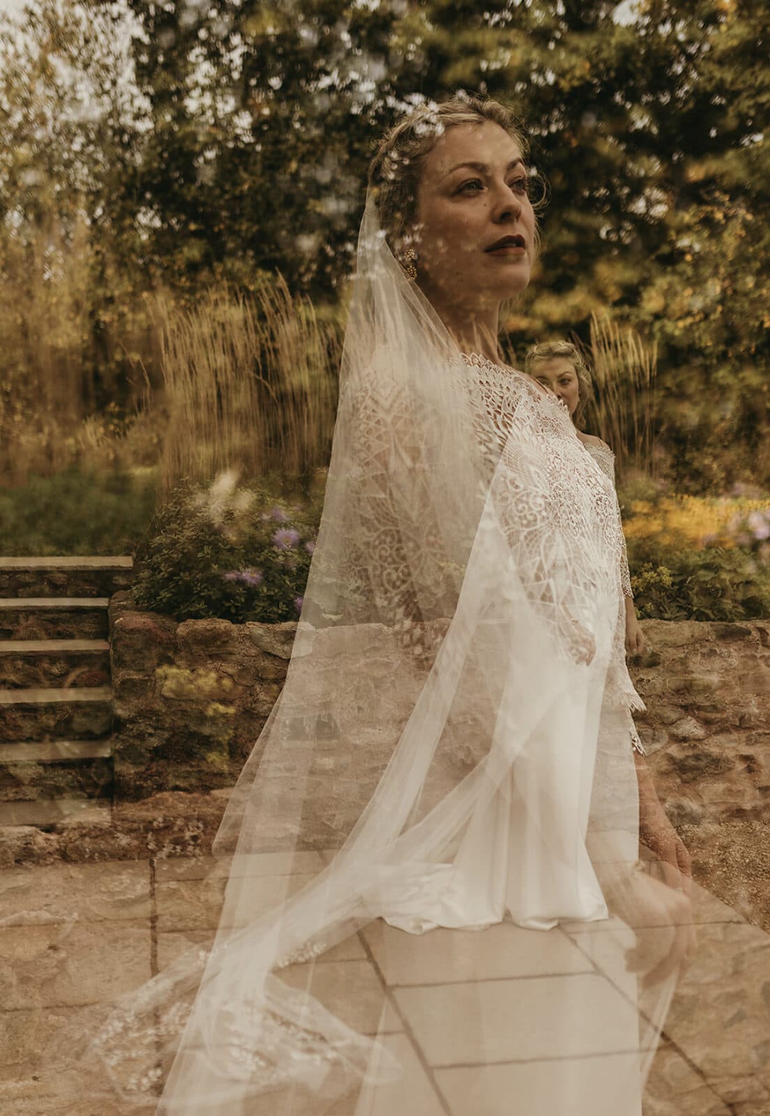 Bride in a long lace veil in a garden